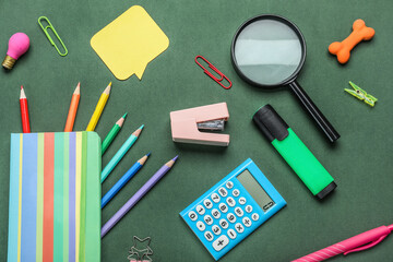 Stapler with different stationery supplies on green background