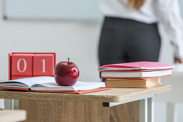 Cube calendar with date 1 SEPTEMBER, apple and school books on table in classroom