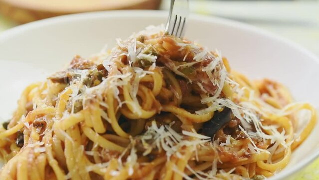 Eating pasta alla norma, served in a plate.
