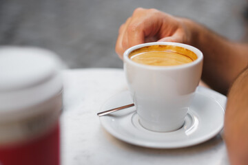 Close up photo of hands holding a cup of coffee in street cafe