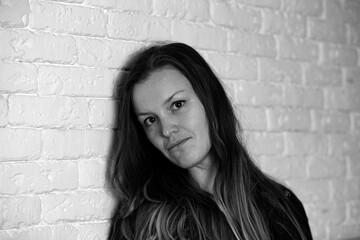 Black and white portrait of beautiful woman on a background of brick wall