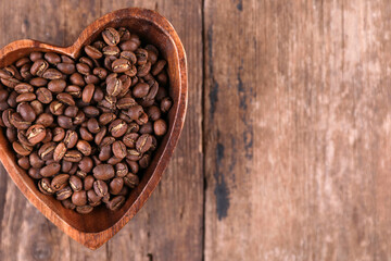 Coffee beans in a wooden bowl on a rustic background