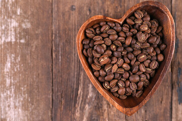 Coffee beans in a wooden bowl on a rustic background