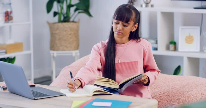 School student doing distance learning with online class and writing notes during a video or zoom call with her teacher. Young high school girl studying and doing research for her assignment at home
