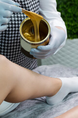 Spa Concepts. Close-up of Beautician Preparing for Wax Depilation of Woman Legs By Applying Liquid Wax With Spatula on Female Legs