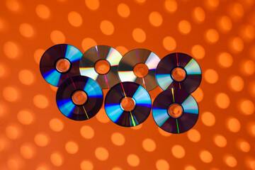Variety of Arranged CD Disks or DVD Disks on Orange Background With Different Round Circular Dotted...