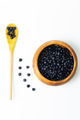 Organic Food Ideas. Heap of Forest Fresh Blueberries in Wooden Bowl With Spoon Over White