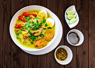 INDONESIAN CULINARY CHICKEN SOUP NOODLE WITH SLICE BOILING EGG AND FRIED MASHED POTATOS AS TOPPING