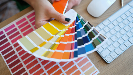 Woman designer holding fan of colourful samples in hand