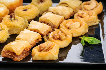 oriental sweets of various types on a large plate on a black background macro photo
