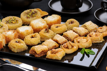 oriental sweets of various types on a large black plate
