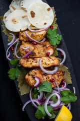 fried chicken shish kebab on a wooden board on a black background macro photo
