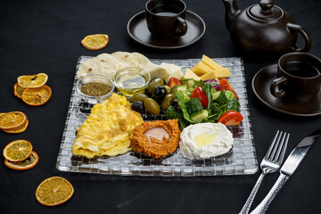 oriental breakfast with hummus and salad and cheese on a black background in a transparent plate macro photo
