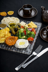 oriental breakfast with hummus and salad and cheese on a black background with spices in a transparent plate macro photo
