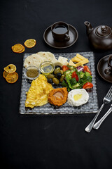 Fototapeta na wymiar oriental breakfast with hummus and salad and cheese on a black background with spices in a transparent plate vertical photo 