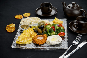 oriental breakfast with hummus and salad and cheese on a black background in a transparent plate macro photo
