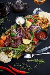 fried meat on the bone shish kebab and chicken on a board with grilled vegetables vertical photo
