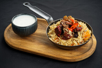 rice pilaf with meat in a pan on a black background
