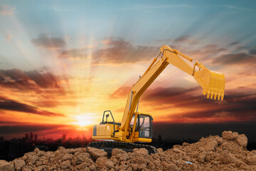 Excavator is digging in the construction site  ,on a sunset background .