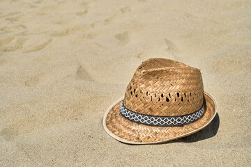 Fototapeta na wymiar Men's straw beach hat on the sand at the beach, close-up, copy space for text. A beautiful sunny day. Vacation, summer concept