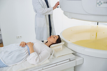 Woman patient is ready to do magnetic resonance imaging MRI or CT scan in clinic
