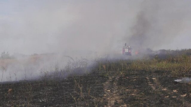 Firefighters put out a fire in a field. great heat warming dry grass is burning.