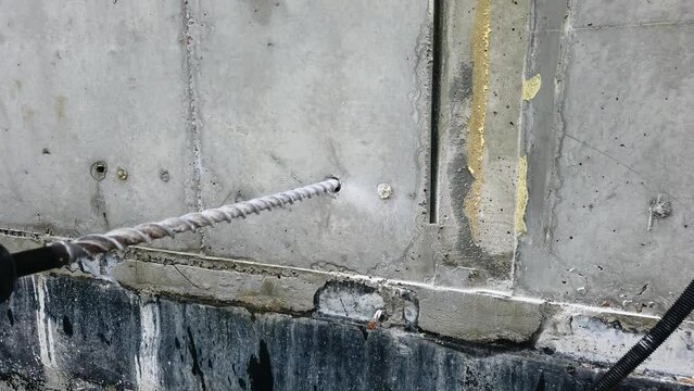Construction worker drills concrete wall with hammer drill perforator
