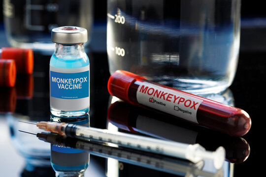 Monkeypox Written vaccine bottle with a blue liquid, a syringe and a blood sample on a laboratory like background.