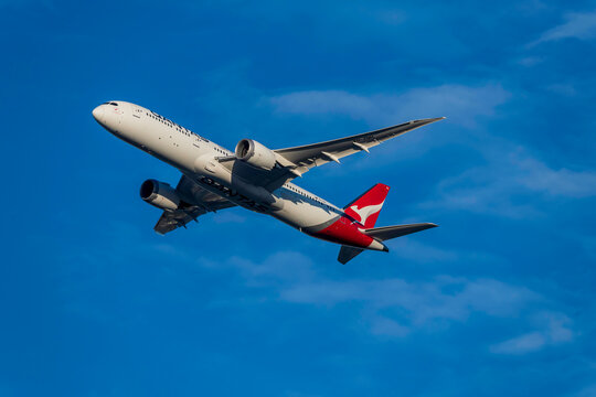 Qantas Airliner in the late afternoon blue sky with light white high cloud flying over Sydney on 14 May 2022.