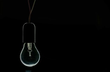turned off incandescent light bulb on a black background - obrazy, fototapety, plakaty