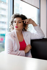 Portrait of a beautiful young woman in a white jacket sitting out the window