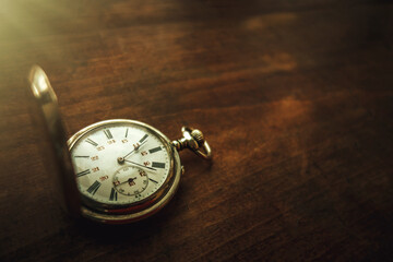 Photo of a mechanical pocket watch on a wooden table.Vintage-style silver watch.