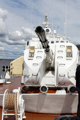 Closeup view of cannon on sea warship against cloudy blue sky