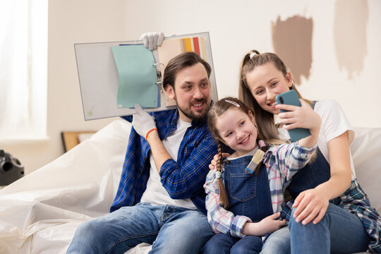 A little 8-year-old girl with a cute smile is holding a phone on which she is taking a selfie. For a family, this is an important period of their life - buying a house, renovating and choosing the