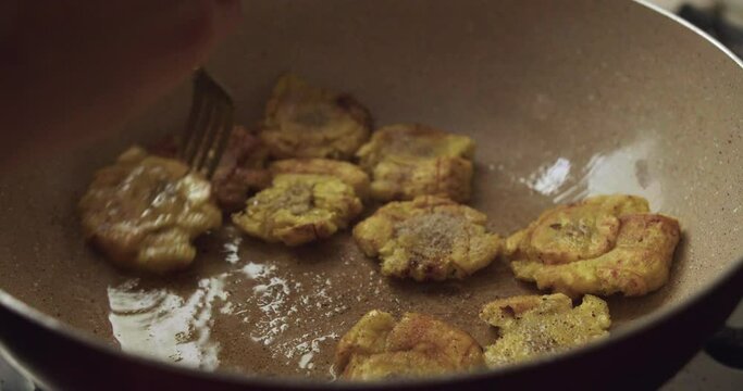 Plano detalle de patacones peruanos cocin&aacute;ndose y fri&eacute;ndose en sart&eacute;n con aceite.