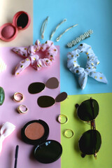 Various accessories, make up products and jewelry on various colorful pastel backgrounds. Selective focus.