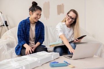 Obraz premium A young Asian beauty woman is happy with the design project of her new apartment prepared for her by a beautiful blonde woman who is an architect. The women get along perfectly with each other, they