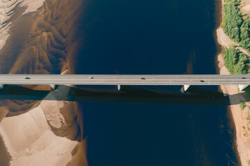 Aerial drone shot of cars driving on bridge over river and sandy riverside at sunset. Amazing...