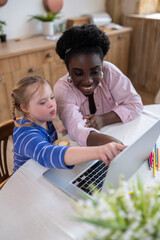 A girl with down syndrome sitting at the laptop with her tutor