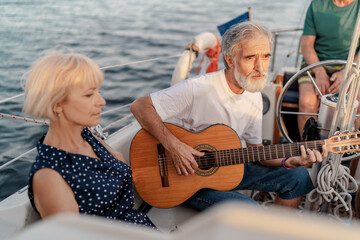 Fototapeta na wymiar Romantic vacation and luxury travel. Senior loving couple sitting on the yacht deck. Sailing the river.