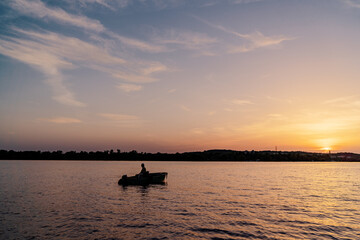 Fishing boat over beautiful sunset background.