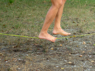 fit young man training walking and balancing on slack line in a park