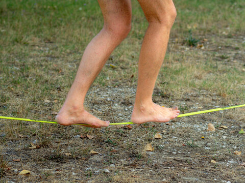 fit young man training walking and balancing on slack line in a park