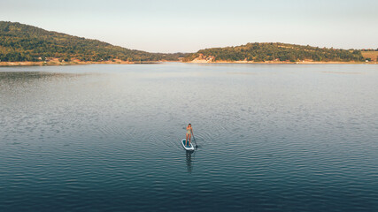 High angle view of woman paddling SUP board on lake.