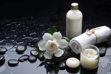 Still life of with 
gardenia, and towel, candle, , zen black stones on wet background
