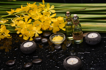 Still life of with 
Yellow orchid  and candle with  green leaves ,oil bottle ,zen black stones on wet background,
