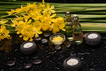 Fototapeten Still life of with  Yellow orchid  and candle with  green leaves ,oil bottle ,zen black stones on wet background,  © Mee Ting