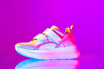 Image of fashionable sports shoes, sneakers isolated over colored neon background. Urban city fashion, fitness, sport, training concept.