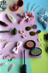 Various accessories, make up products and jewelry on various colorful pastel backgrounds. Selective focus.