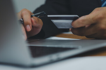 Man hand holding credit card using Internet technology digital to pay for his purchases and shopping online on a computer.